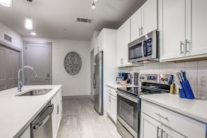 A modern kitchen with stainless steel appliances, white cabinetry, and a built-in microwave. - Luxury Riverwalk Condo Pool, Balcony, Parking (San Antonio)