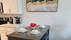 Ein Essbereich mit einem dunklen Holztisch, weißen Tellern und einer Vase mit roten Blumen.