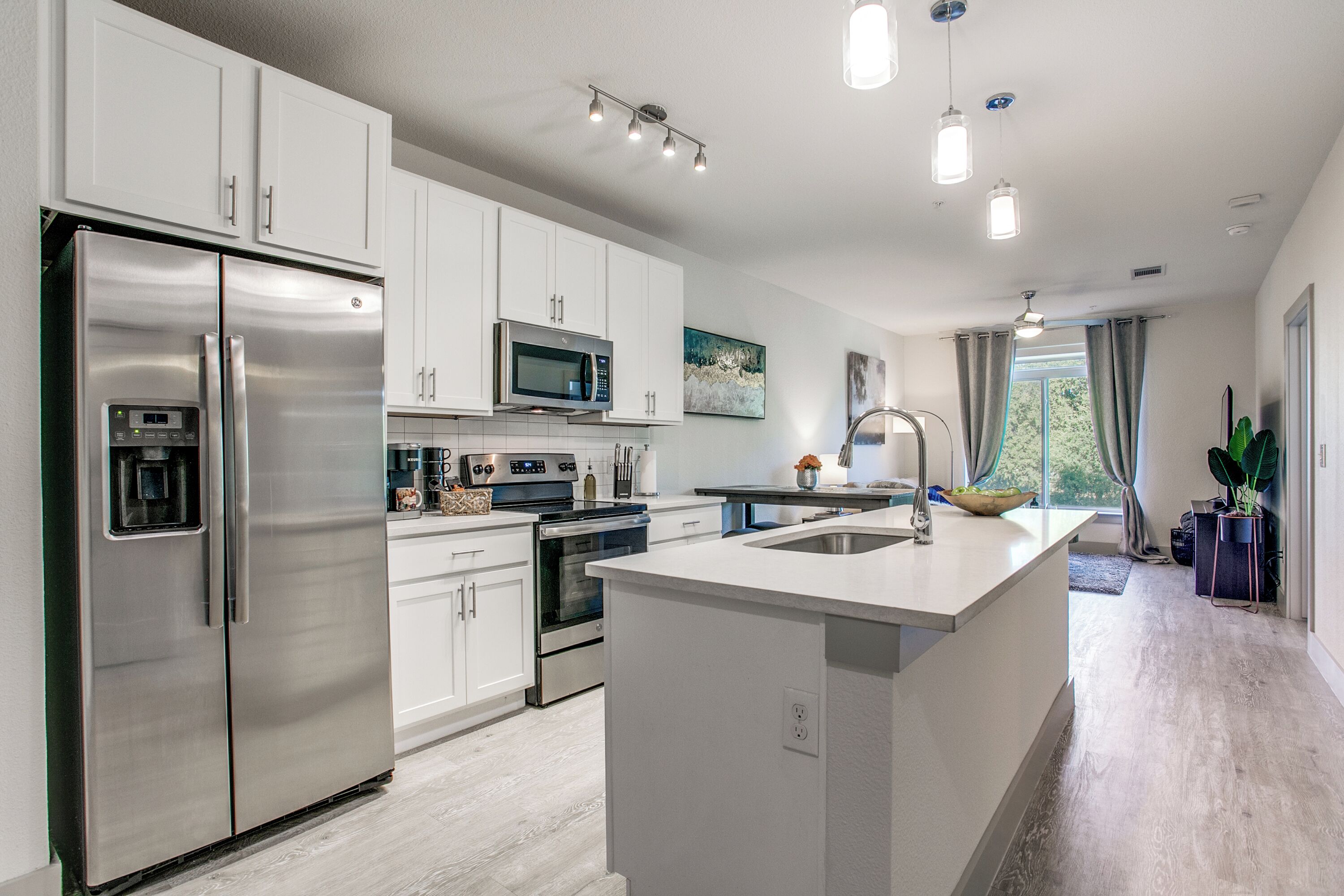 A modern kitchen with stainless steel appliances, white cabinetry, and a central island.