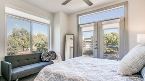Ein Schlafzimmer mit einem Bett, einer Couch, einem Deckenventilator und großen Fenstern.