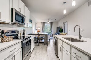 Una cocina moderna con armarios blancos, electrodomésticos de acero inoxidable y una isla central con asientos.