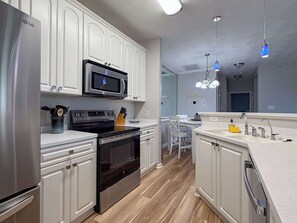 Una cocina moderna con armarios blancos, electrodomésticos de acero inoxidable y piso de madera.