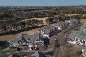 Zona residencial con varias casas, un lago y un faro en la distancia.