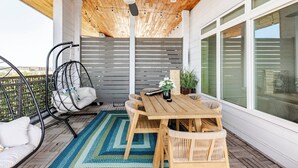 A wooden deck with a ceiling fan, a table with chairs, and a hanging chair. - Luxury Riverwalk Penthouse Pool & Skyline Views (San Antonio)