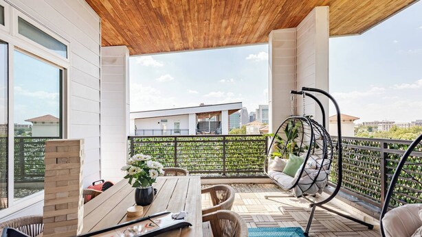 A wooden ceiling, a table with chairs, a hanging chair, and a view of buildings. - Luxury Riverwalk Penthouse Pool & Skyline Views (San Antonio)