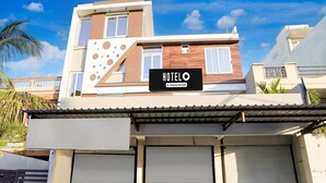 Un hotel moderno con un letrero que dice 'HOTELO' y un logotipo de la empresa. Tiene un techo plano, una gran puerta de garaje y una fachada distintiva con diseños circulares.