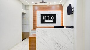 Un mostrador de recepción de hotel con encimera de mármol, una pared decorativa de madera y un ventilador de techo.