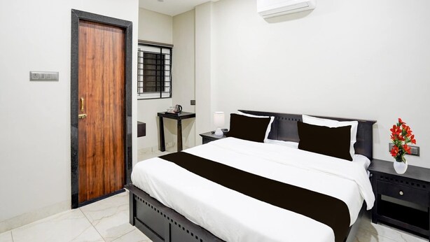 Un dormitorio con cama, mesitas de noche, ventana con vistas y unidad de aire acondicionado.