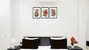 Habitación de hotel con cama, mesitas de noche, lámpara, teléfono y cuadros en la pared.