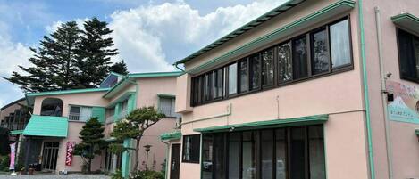 A building with a pink facade, green trim, and large windows.