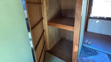Una habitación pequeña y cerrada con suelo de madera, un ventanal y un par de zapatos en el alféizar.