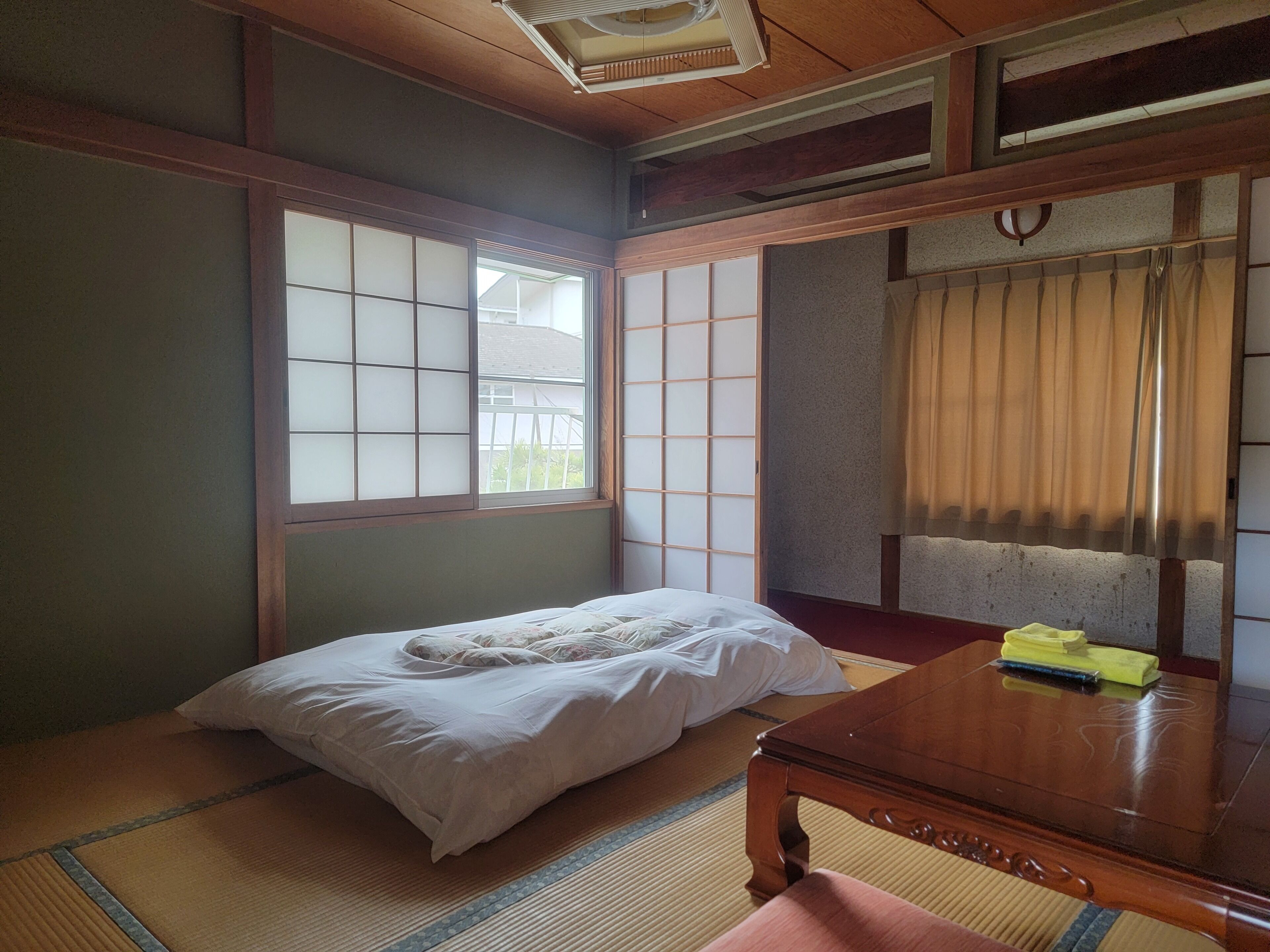 A traditional Japanese room with tatami flooring, a low wooden bed, a wooden table, and shoji screens.