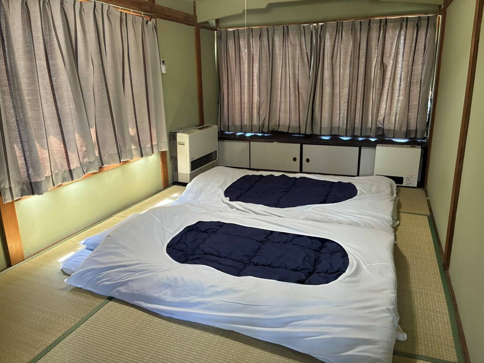 A room with a bed, a heater, and a window with curtains.