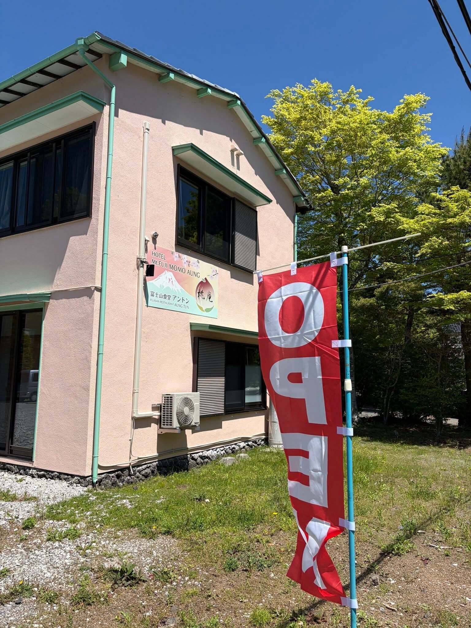 A building with a sign for a hotel and restaurant, a flag, and a clear sky.
