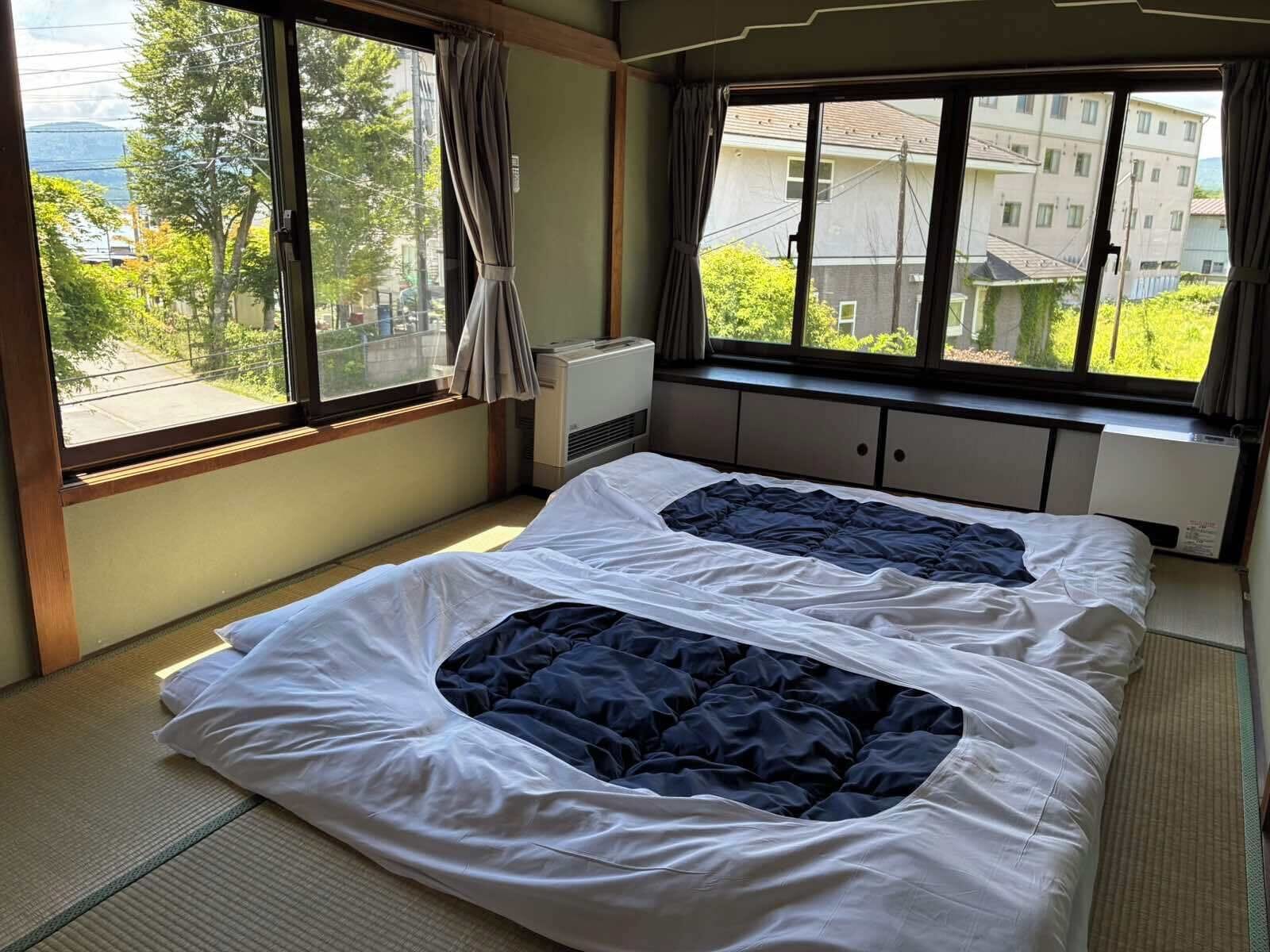 A room with a bed, a window with curtains, and an air conditioning unit.