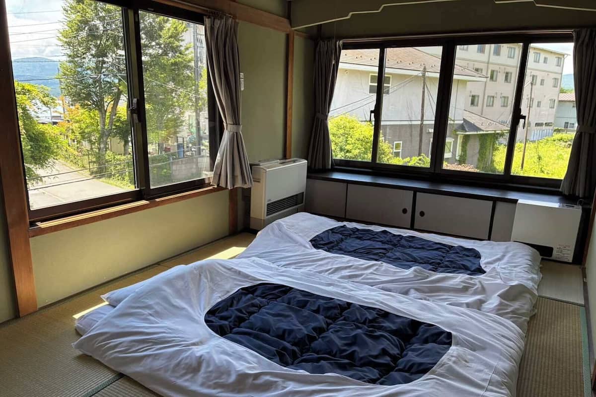 A room with a bed, a window with curtains, and an air conditioning unit.