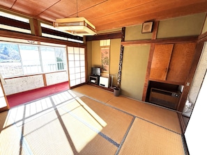 A traditional tatami mat room with a television, a small shelf, and a sliding door. - HOTEL Mt.Fuji MoMoAung (Yamanakako)