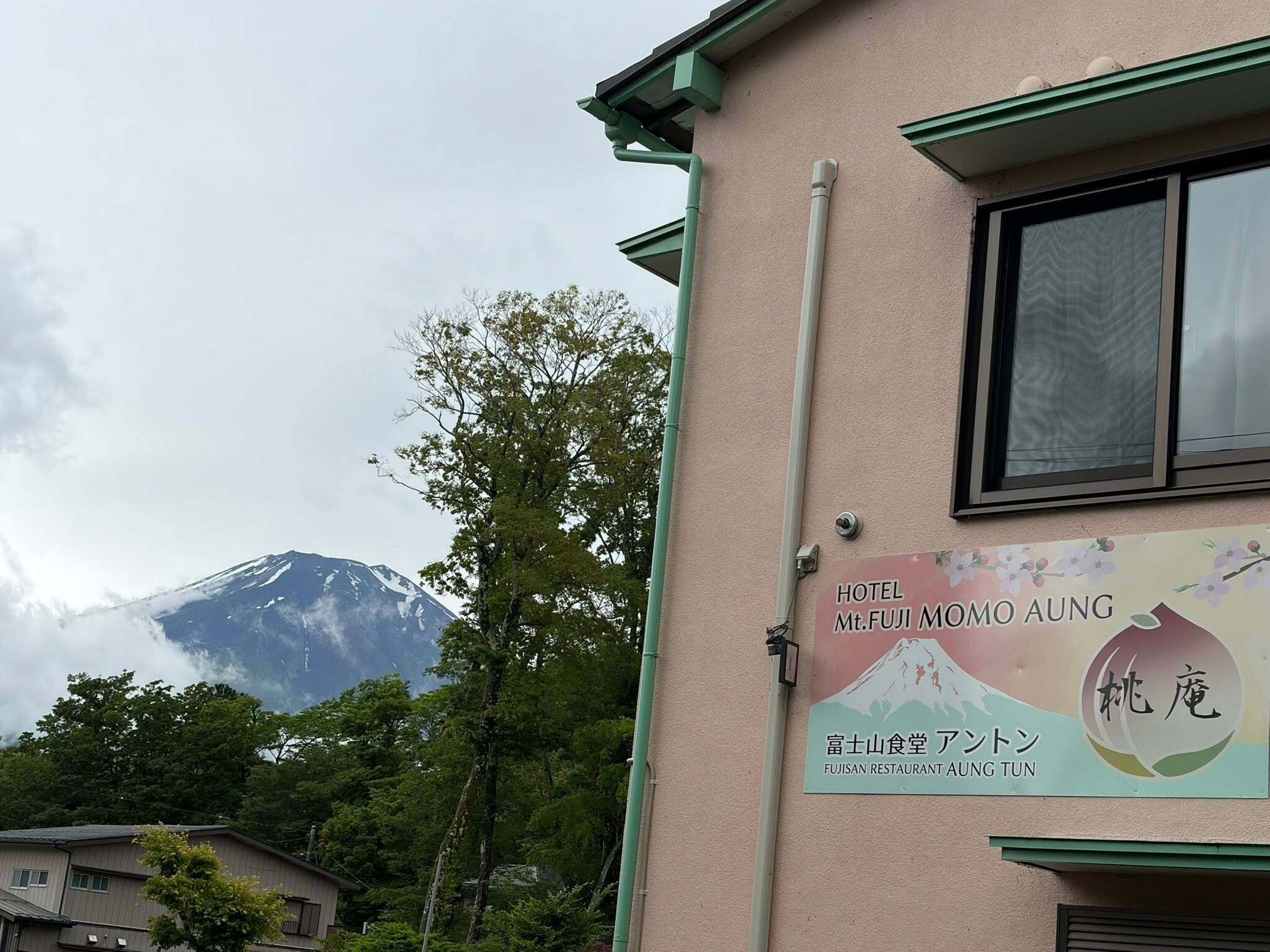 Un bâtiment sur lequel on peut lire les enseignes « Hôtel Mont Fuji Momoko Aung » et « Restaurant Fuji San Aung Tun », avec une montagne en arrière-plan.