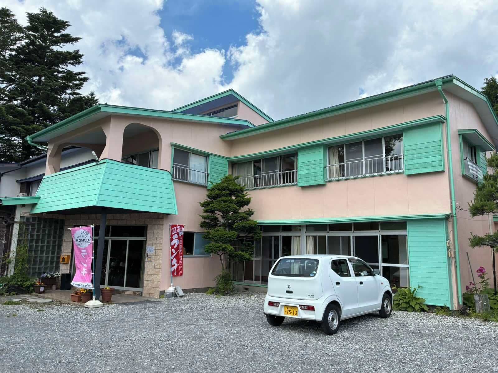 A two-story building with a car parked in front.