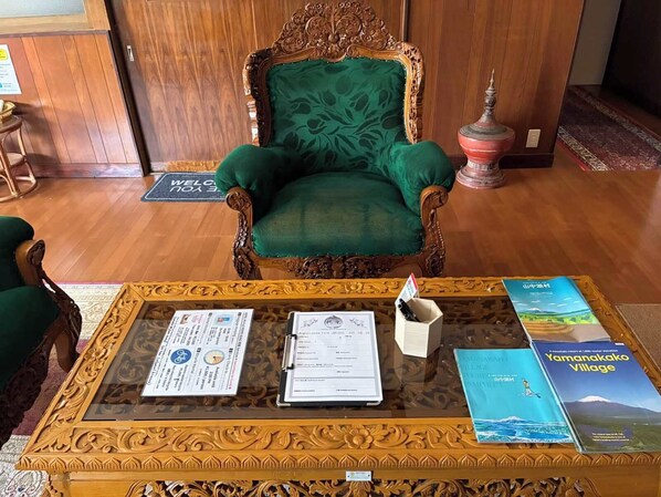 A room with a green upholstered chair, a wooden table with documents, and a brochure on the table. - HOTEL Mt.Fuji MoMoAung (Yamanakako)