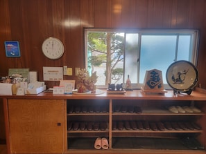 A wooden counter with a clock, a framed picture, and a window with a view of trees. - HOTEL Mt.Fuji MoMoAung (Yamanakako)