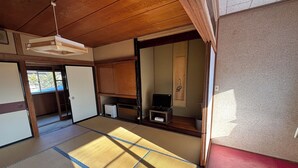 A traditional Japanese room with tatami flooring, a television, a small cabinet, and a sliding door.