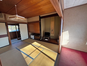 A traditional Japanese room with tatami flooring, a television, a small cabinet, and a sliding door. - HOTEL Mt.Fuji MoMoAung (Yamanakako)