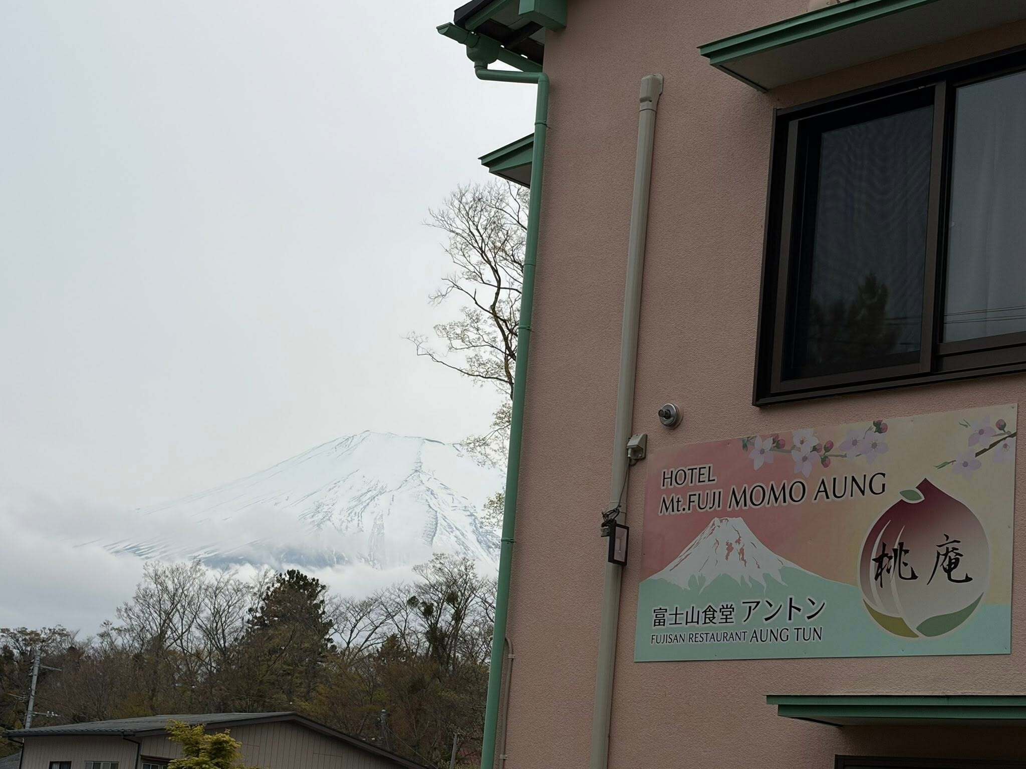 A building with a sign for Hotel Mt. Fuji Mo Aung, featuring a mountain view.