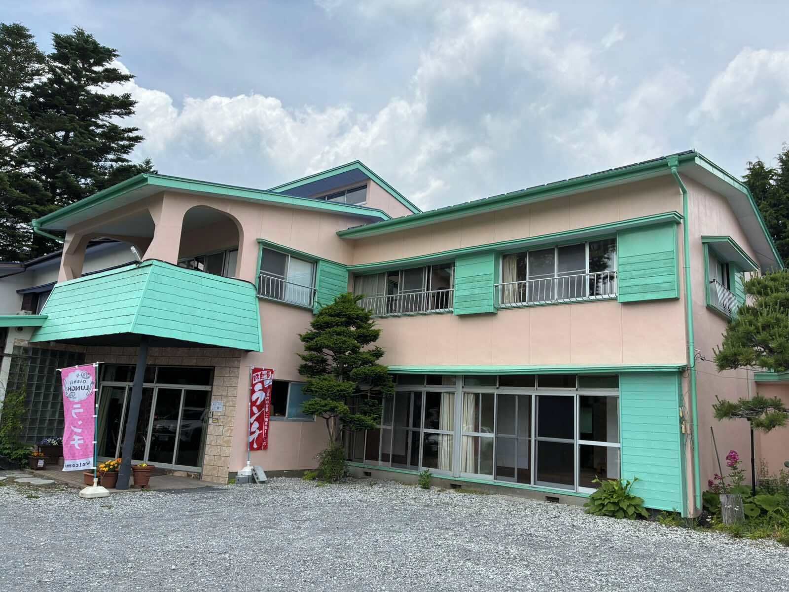 A two-story building with a green roof, large windows, and a small balcony.