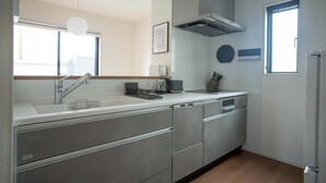 A modern kitchen with a built-in dishwasher, a stainless steel sink, and a window providing natural light. - Bright 4BR Home in Ozu Sleeps 11 by Restavio (Ozu Town, Kikuchi District)
