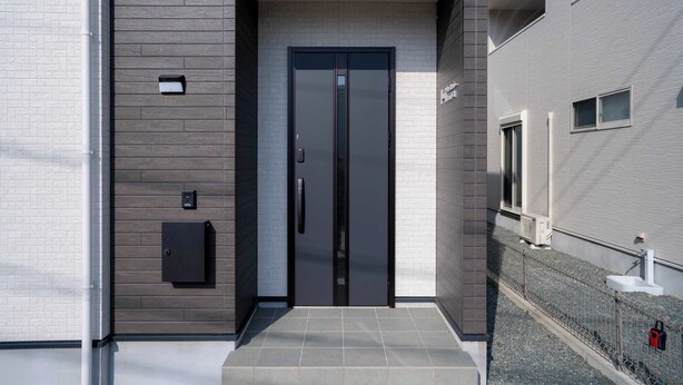 A modern building entrance with a double door, a small mailbox, and a security camera. - Bright 4BR Home in Ozu Sleeps 11 by Restavio (Ozu Town, Kikuchi District)