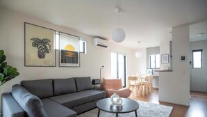 A modern living room with a grey sofa, a round coffee table, and a dining area with a table and chairs. - Bright 4BR Home in Ozu Sleeps 11 by Restavio (Ozu Town, Kikuchi District)