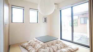 A room with a bed, large windows, a ceiling light, and a picture on the wall. - Bright 4BR Home in Ozu Sleeps 11 by Restavio (Ozu Town, Kikuchi District)