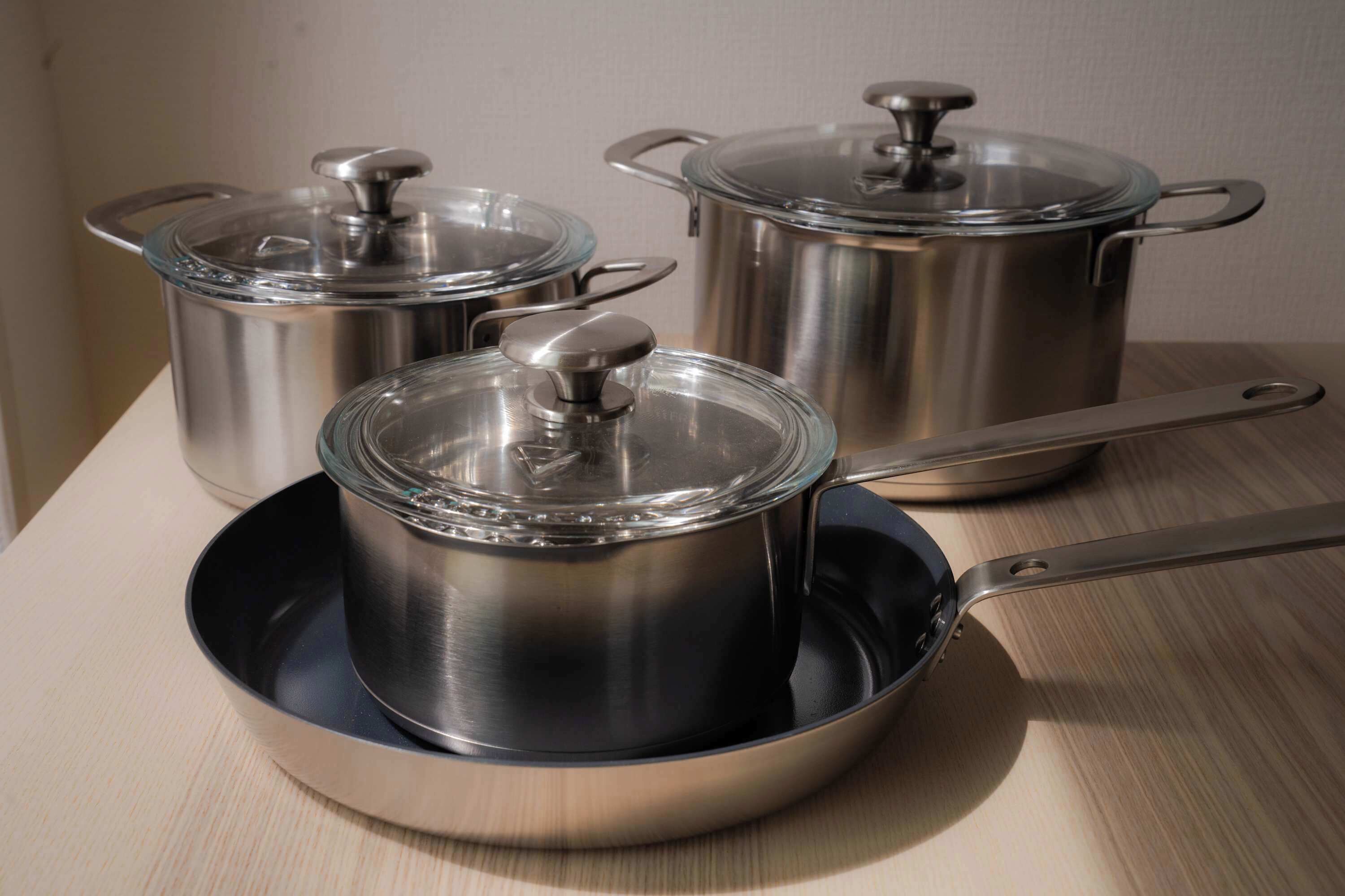 Utensilios de cocina de acero inoxidable con tapas sobre una superficie de madera.