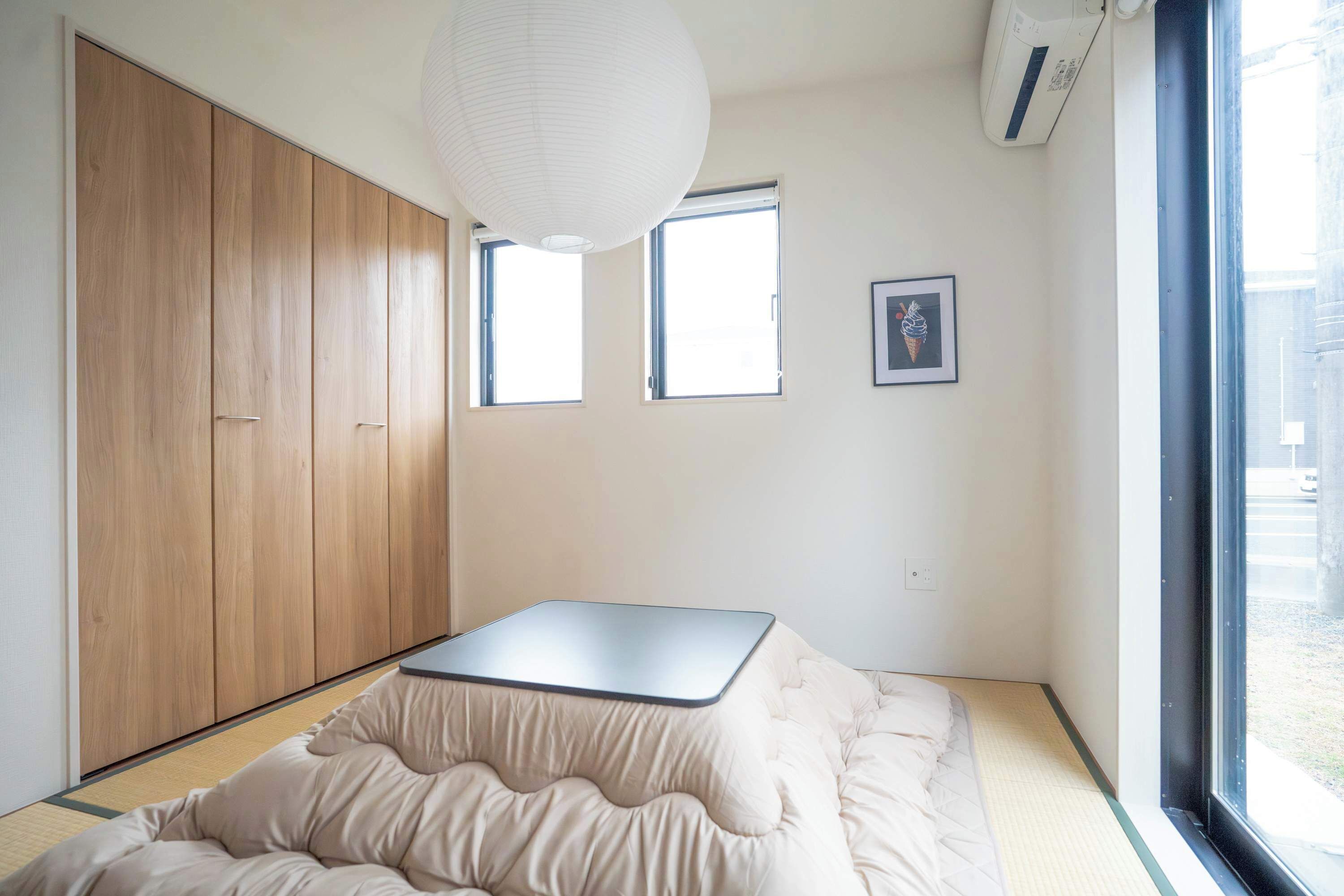 Een kamer met een bed, een kledingkast, twee ramen en een hanglamp.