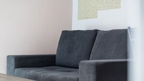Um sofá cinzento numa sala com uma mesa de madeira e uma parede com padrão texturizado.