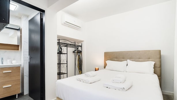 Quarto de hotel com cama, guarda-roupa, banheiro com chuveiro e aparelho de ar condicionado.