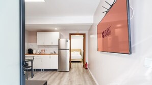 Quarto de hotel moderno com cozinha compacta, uma cama e um aviso 'Guest Ready' na parede.