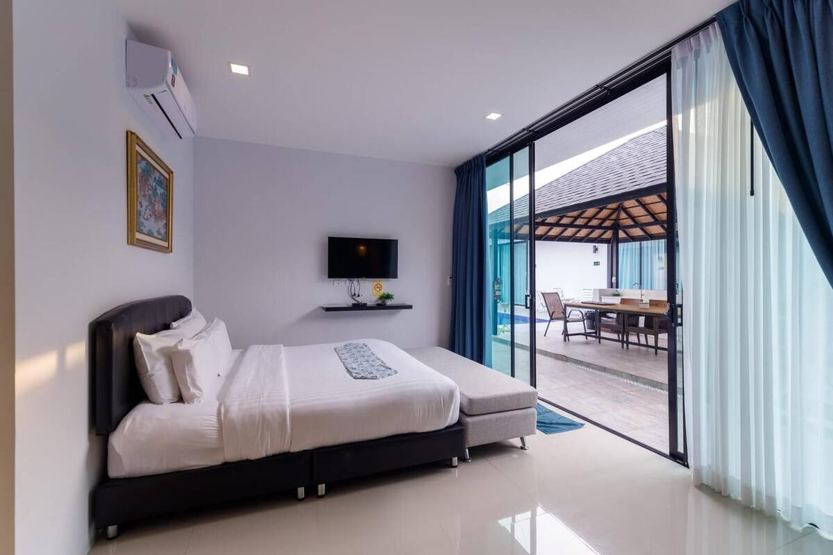Una habitación de hotel moderna con cama, televisión, una mesita y un balcón con vistas.