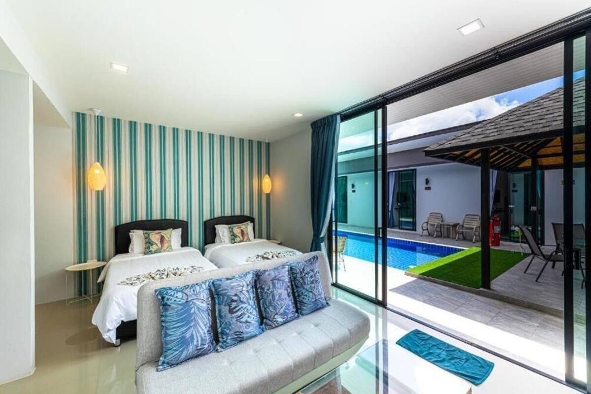 Habitación de hotel con dos camas, un sofá, un ventanal grande y vista a una piscina.