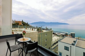 Ein Balkon mit Tisch und Stühlen mit Blick auf eine Küstenlandschaft mit Gebäuden und einem Wasserspiegel.
