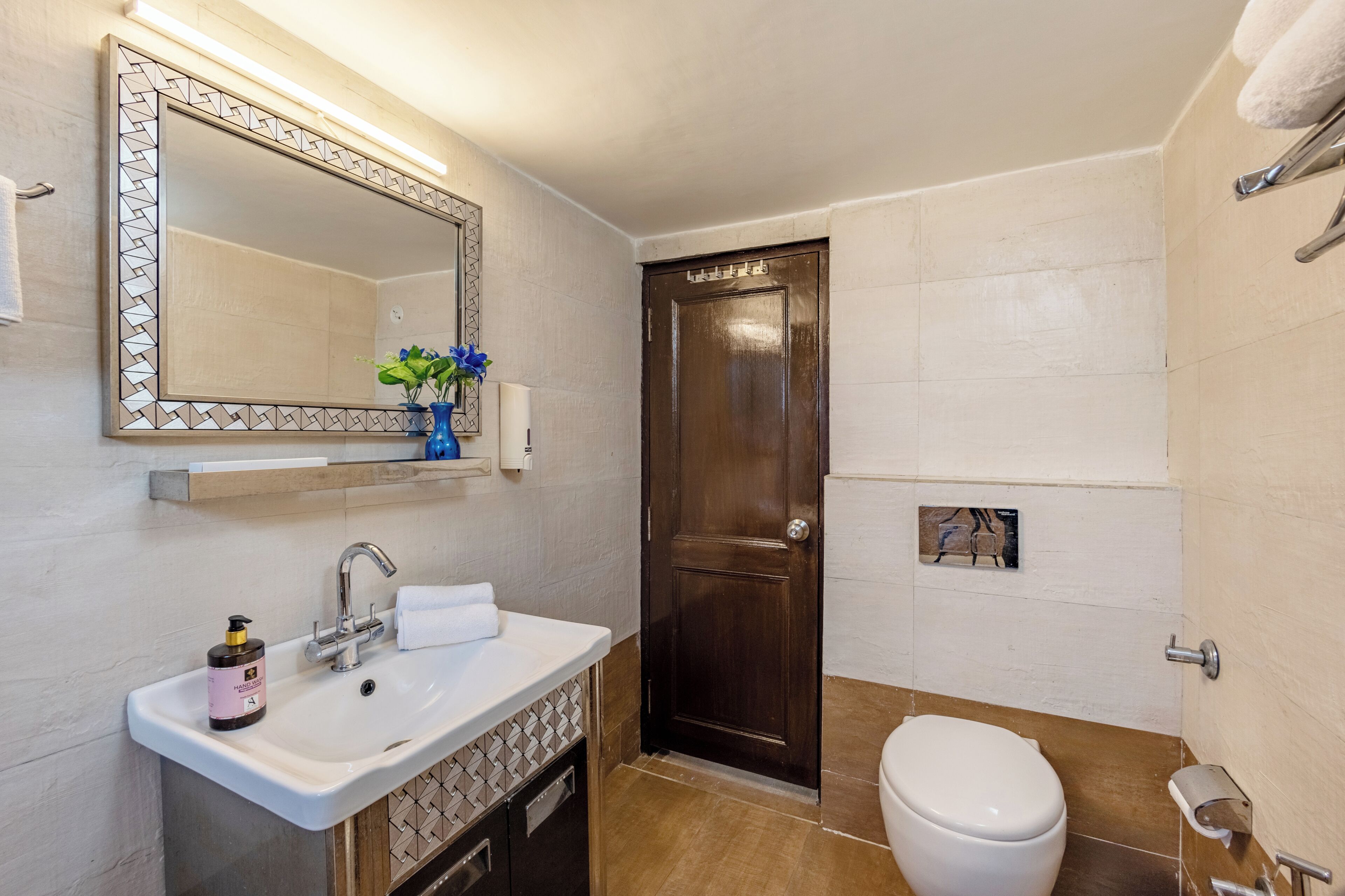 Un baño con lavamanos, espejo e inodoro.