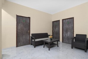 A room with a sofa, a chair, a table, and two doors. - Collection O Biswa Bangla Convention Centre (Barasat)