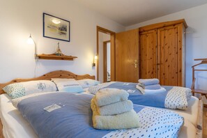 Ein Schlafzimmer mit zwei Betten, einem Holzschrank und einem Regal mit einem Schiffsmodell.