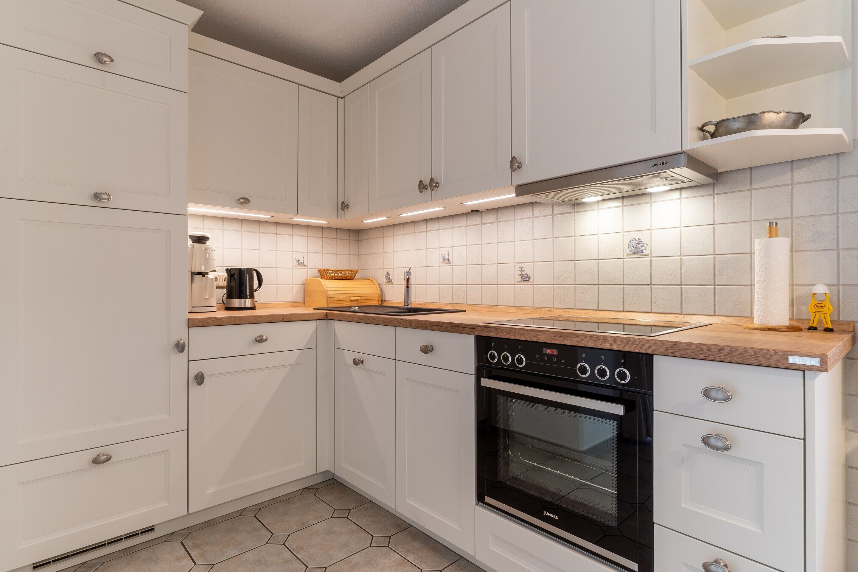 A modern kitchen with white cabinets, a black oven, and a wooden countertop.