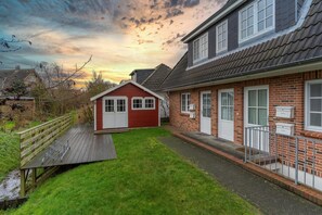 Ein Wohnhaus mit rotem Haus, einer Holzterrasse und einer Ziegelaußenwand.