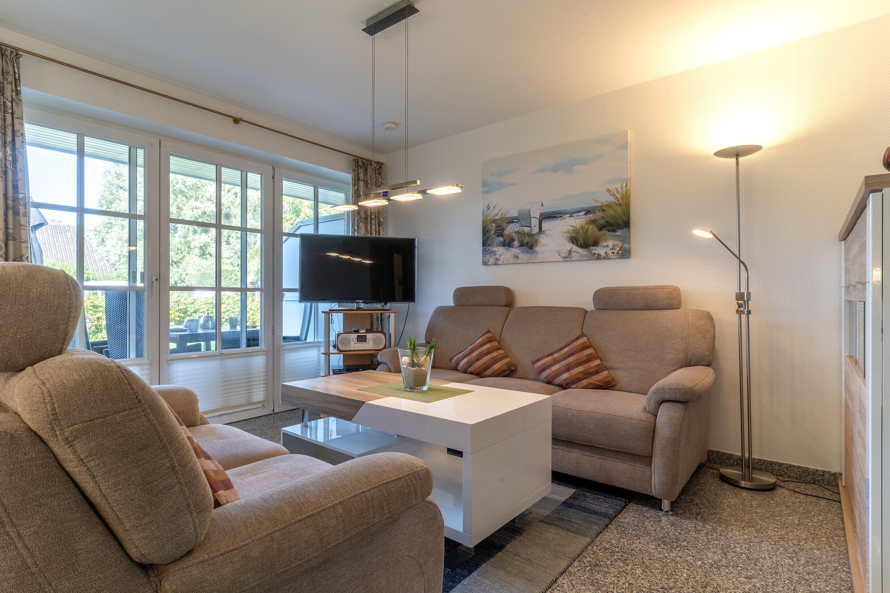 A modern living room with a sofa, a coffee table, a flat-screen TV, and a painting on the wall.