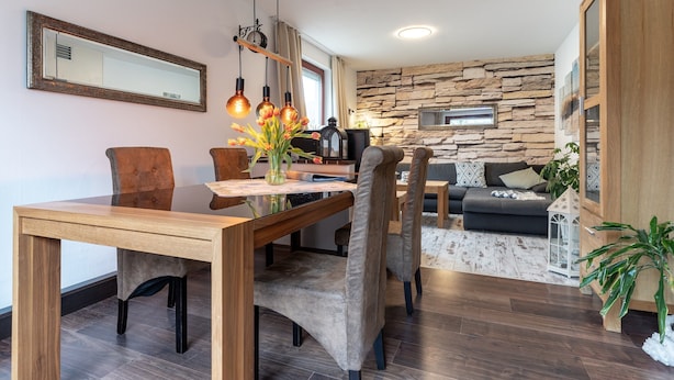 A modern living space with a dining area, a stone wall, and a wooden cabinet. - Ferienwohnung in Busum (Büsum)