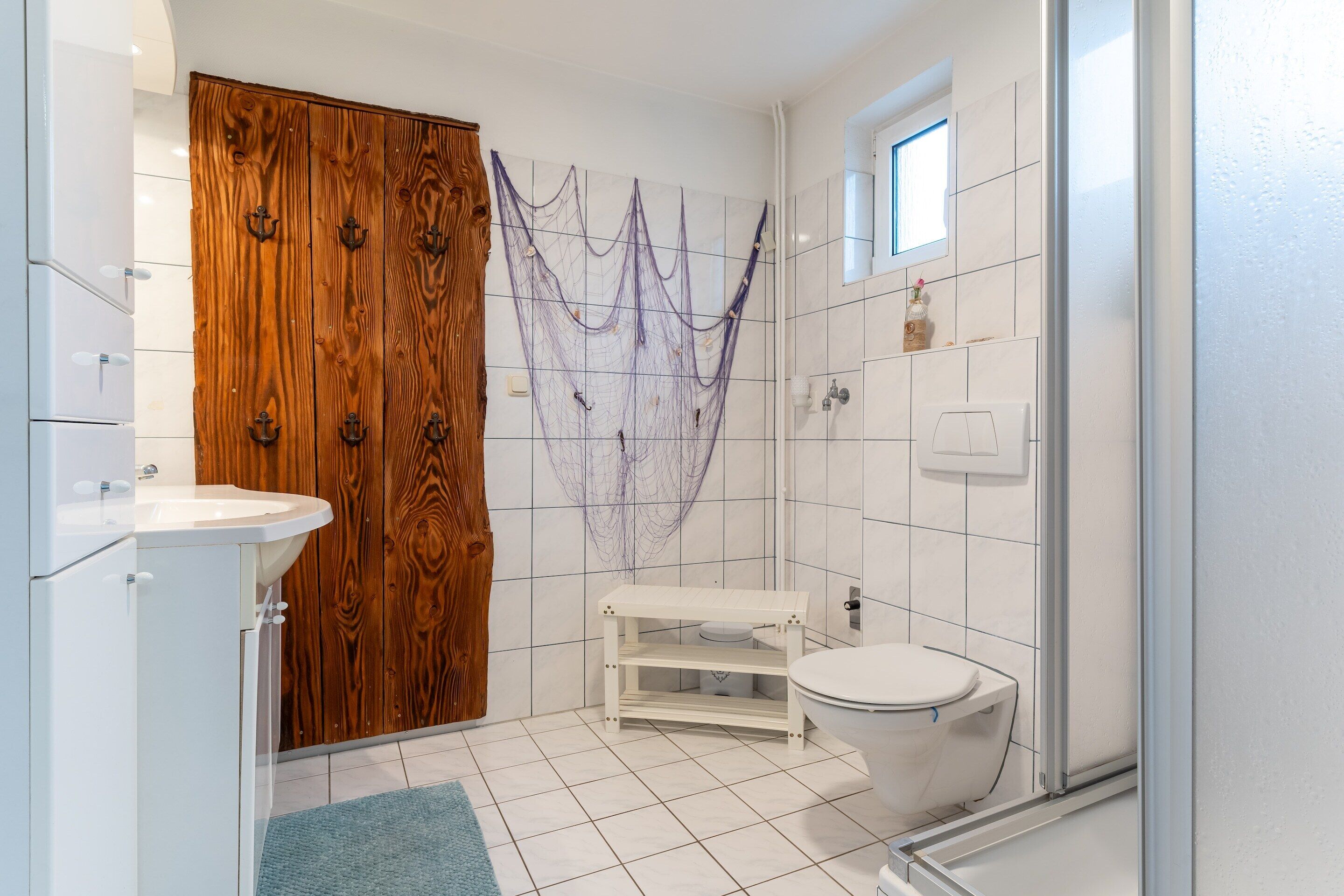 A bathroom with a wooden door, a white sink, a toilet, and a shower area.
