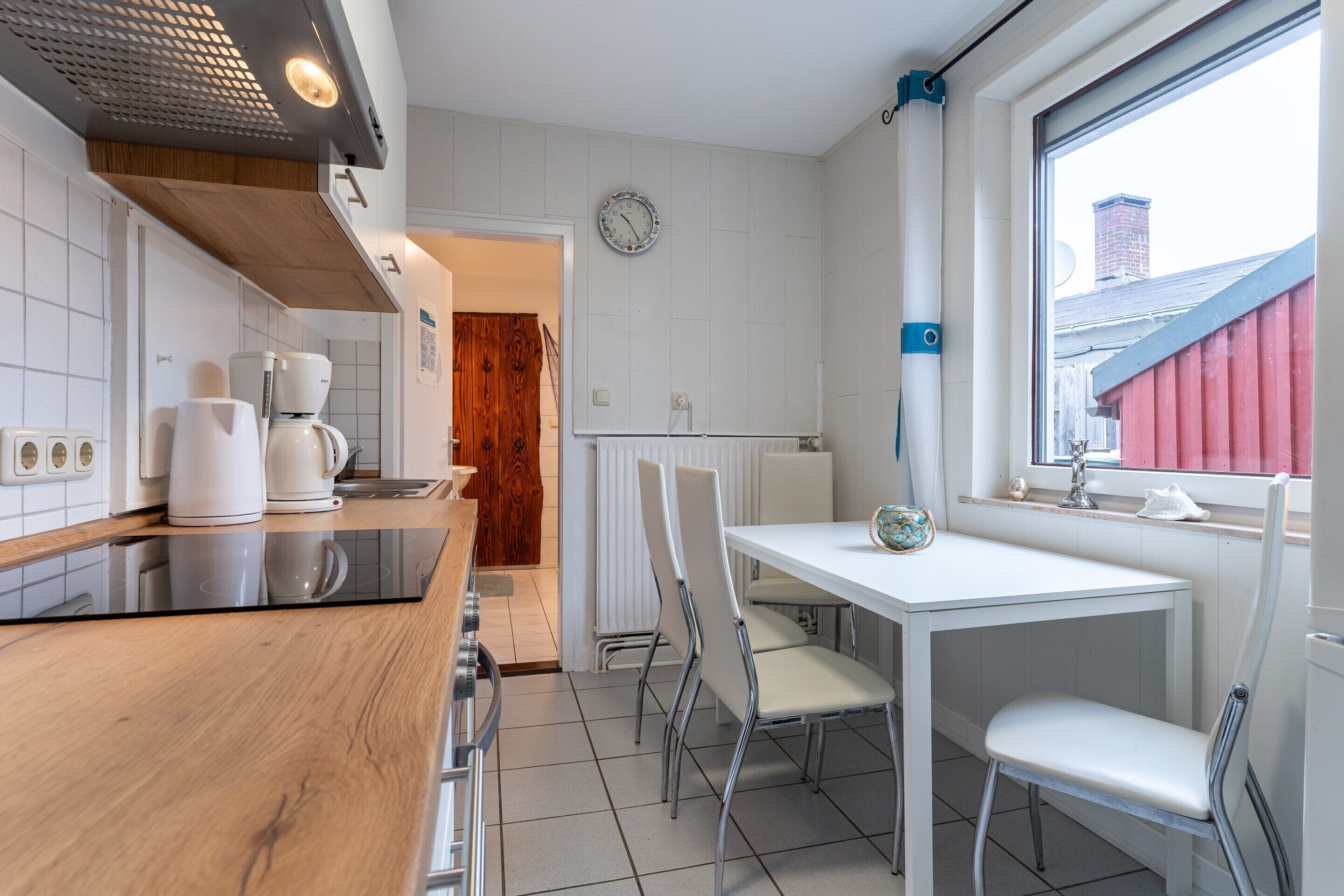 Une cuisine moderne avec un plan de travail en bois, des armoires blanches, une machine à café et un coin repas comprenant une table et des chaises.